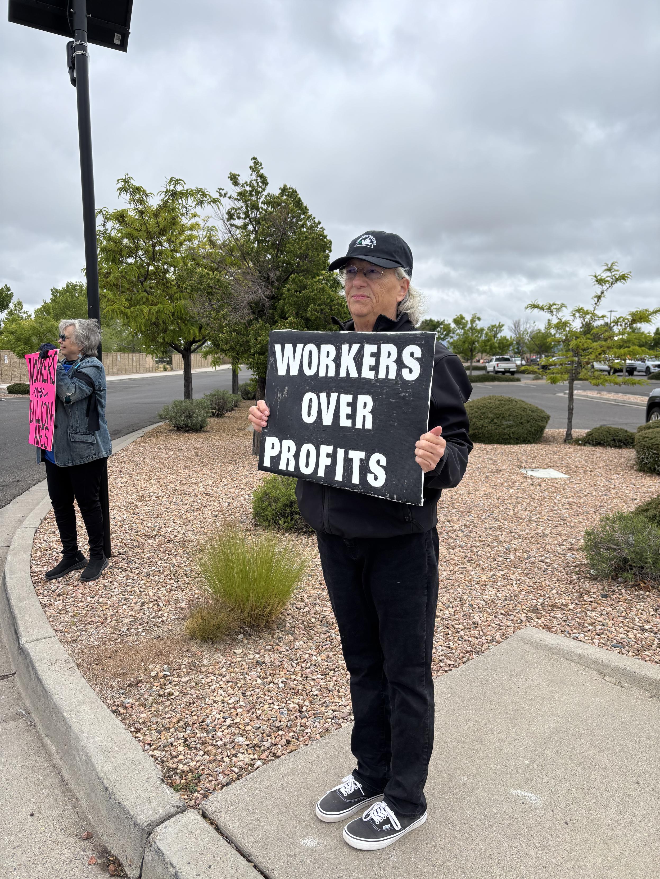 Woman with sign reading WORKERS OVER PROFITS.