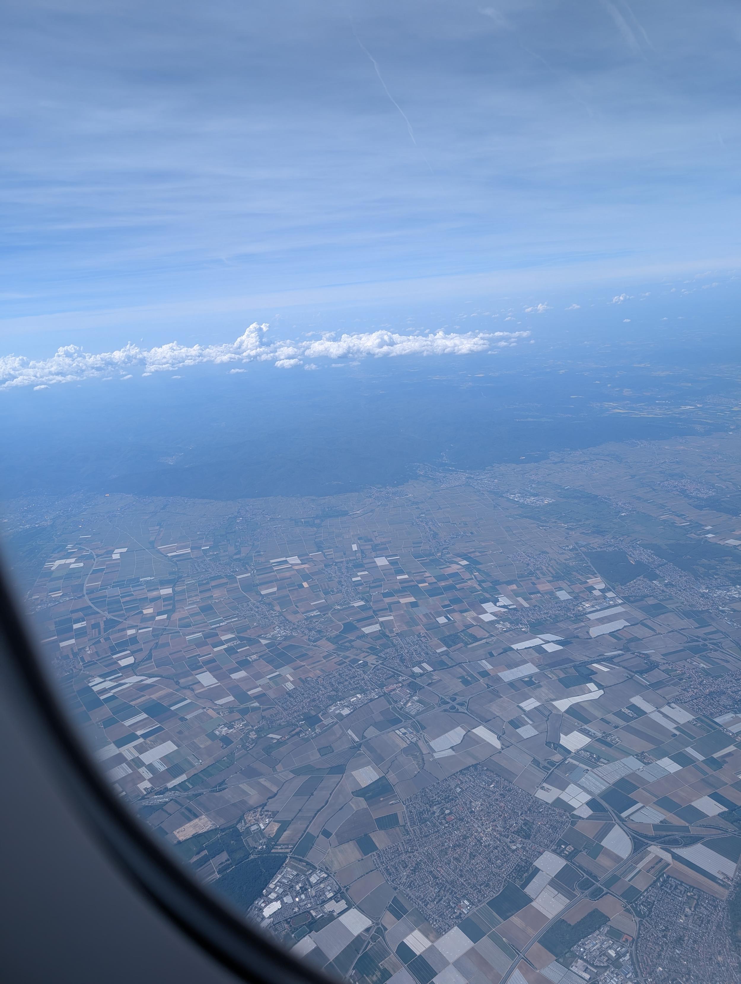 View outside airplane window showing clouds and stuff on the ground
