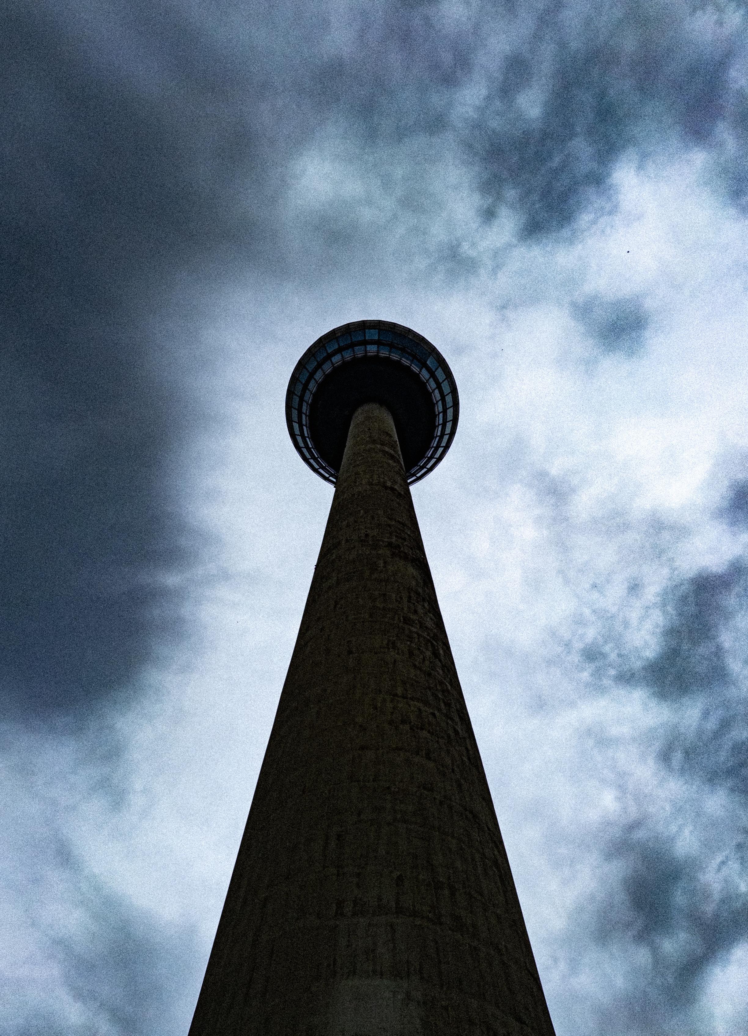 Looking up at the Funkmeldeturm just outside Mannheim, seen against cloudy sky. The picture has been pushed for contrast, making the tower dark and the clouds a mix of light and dark.