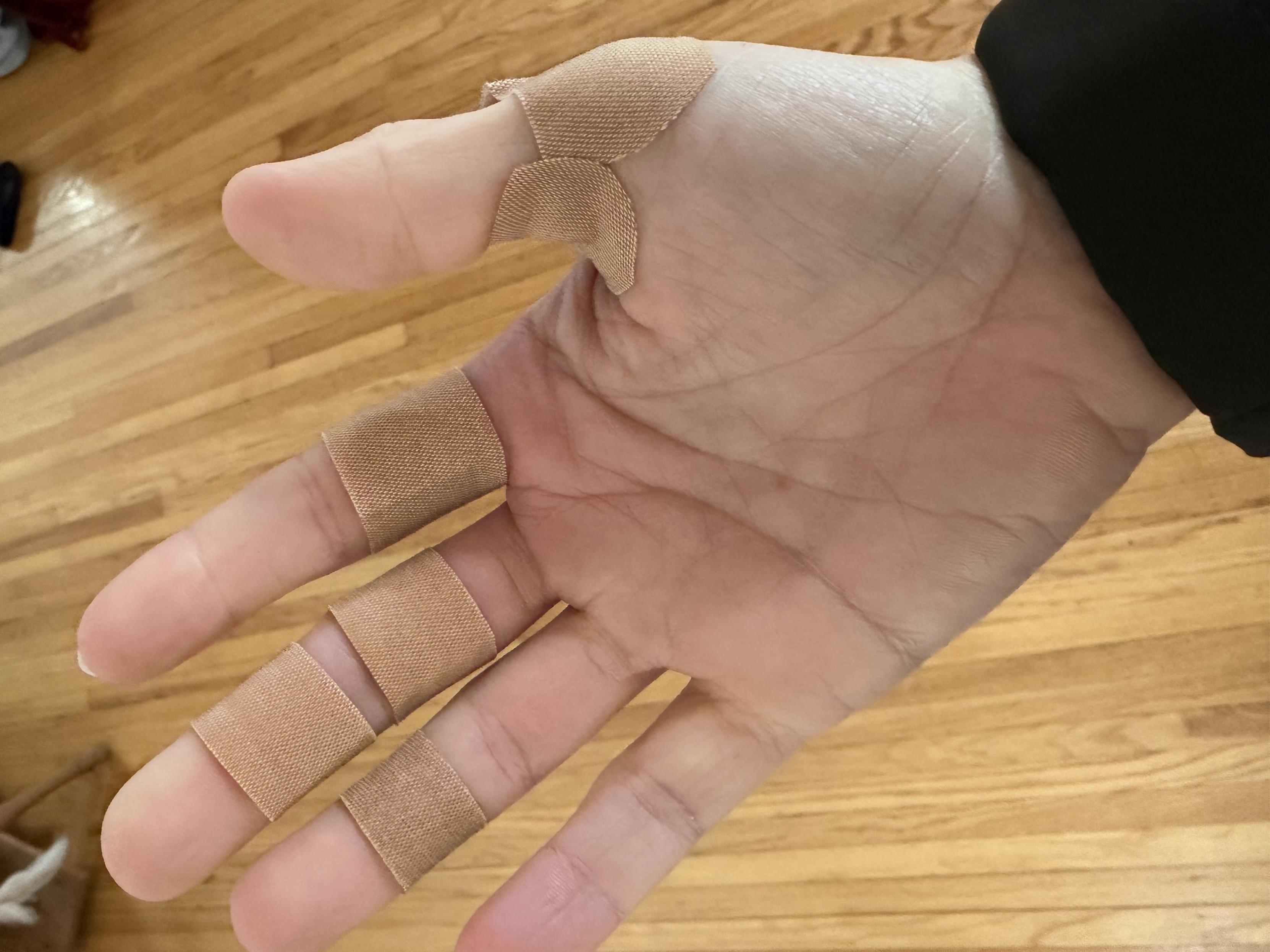 A hand with five bandages on the fingers. The photo has been rotated by 90° so the bandages are roughly aligned vertically instead of horizontally.