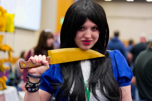 Girl with long black hair holds knife to throat wearing blue dress