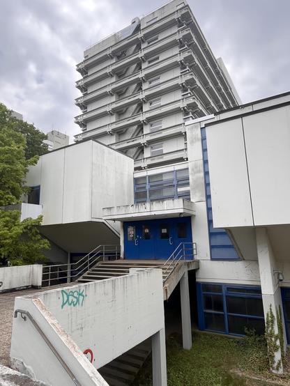 Hochhaus mit viel Sichtbeton, davor Treppen und Terrassen 