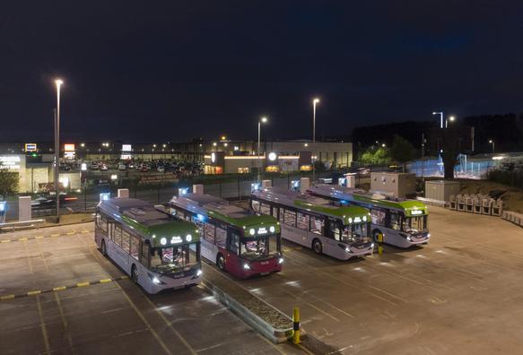 Four buses at a bus depot at night