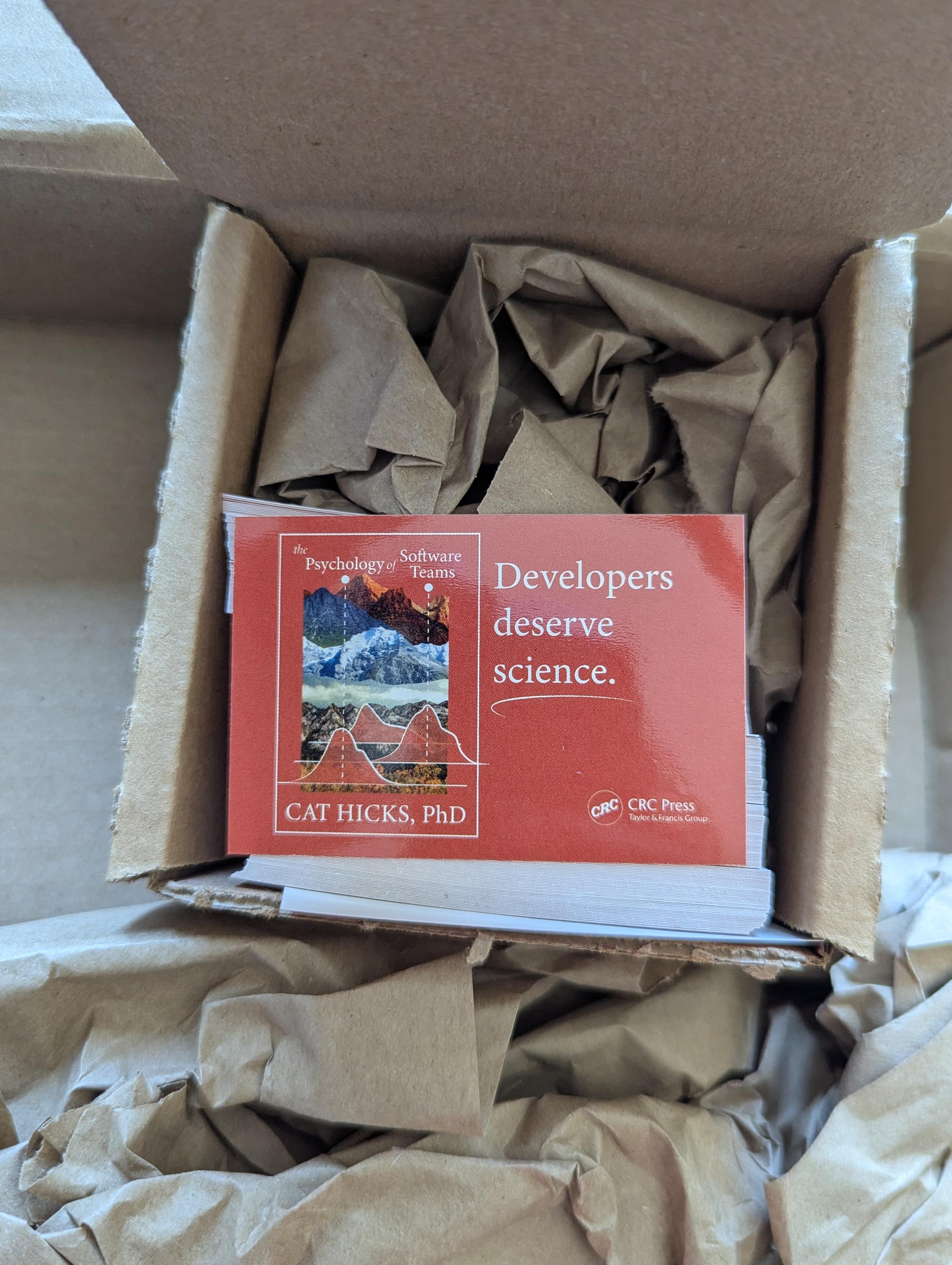 A sticker shows a tiny book cover of the Psychology of Software Teams on a terracotta background, and white text reads Developers Deserve Science