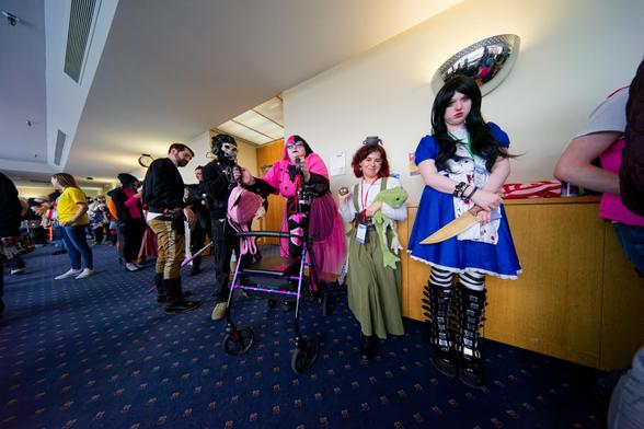 Several cosplayers including somebody purple with a walked and an evil alice are lined up on the right