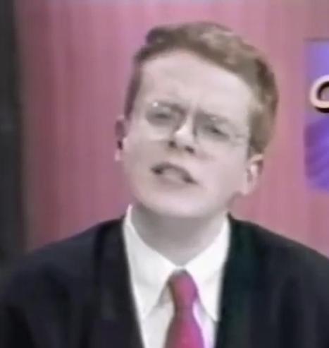 In the year 1999 or so, Bill appears dressed as a TV news anchor and seems to be wincing in mid-word