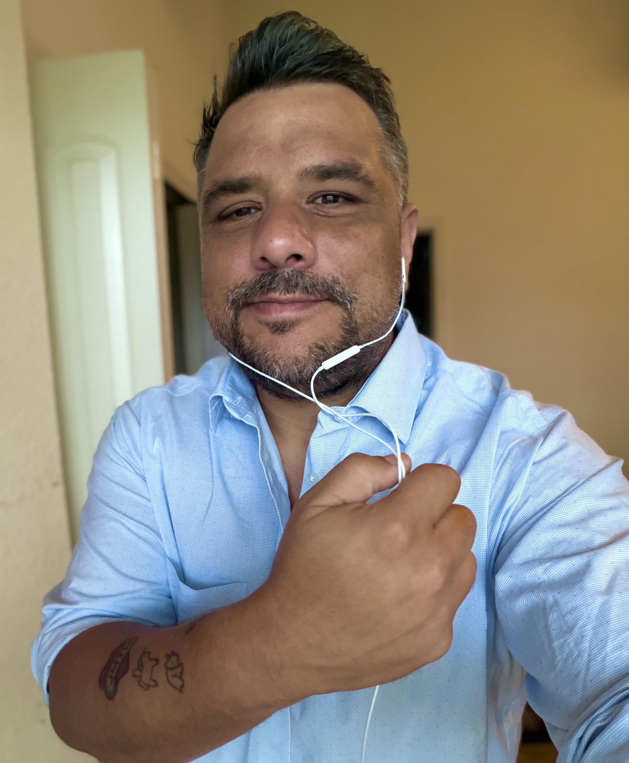 Me in a button down shirt, blue. Holding the wire of white earbuds 