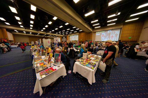 Tables of comic book convention merchandise seen corner-on with geometrically stunning rectangular light field above