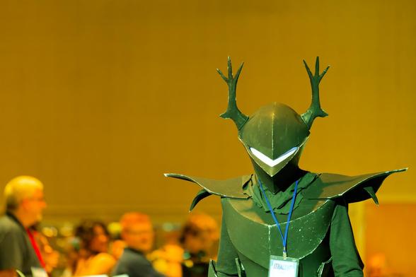 Person in bug-like green costume in yellow tinted room