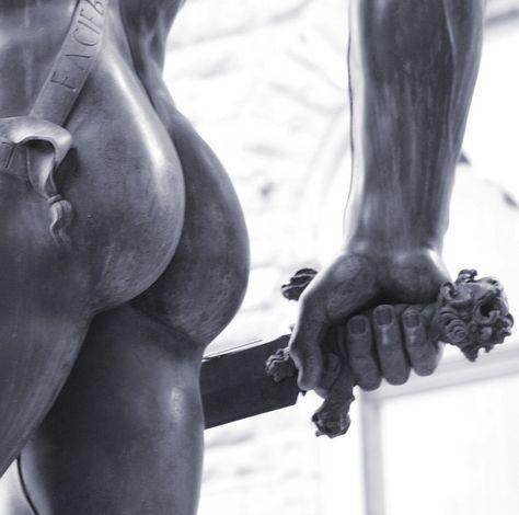 Black-and-white close-up photograph of Cellini's Perseus sculpture. The shot shows his naked buttocks centre-left and his forearm with his hand holding the sickle-sword centre-right.