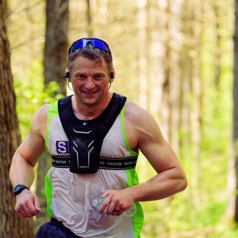 Muscular man with white tank top with green rip and a set of googles riding over his short hair