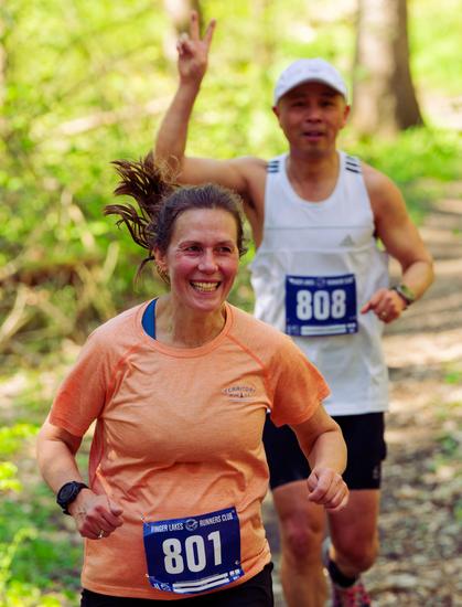 Below and closer to me is a woman in a peach shirt and behind her an asian man wearing a white tank top and holding up his hand
