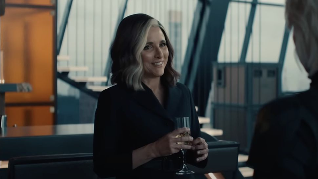 Valentina Allegra de Fontaine holding a glass in the renovated Avengers Tower, facing to her left the same as Tulsi Gabbard in the previous photo but with a smile