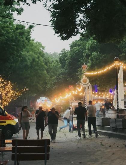 Menschen an der Schlachte in Bremen unter Lichterketten, im Hintergrund Bäume. Die ersten Gewitterböen kommen gerade, die Menschen bedecken ihre Augen oder laufen.