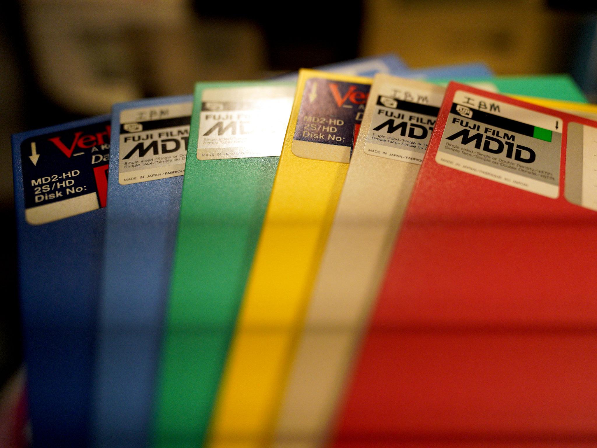 Six 5¼" floppy disks fanned out like a hand of cards.

The dark blue (standing in for purple) and yellow disks are high-density Verbatim media, while the light blue, green (more turquoise, but as close as I could get), beige (very very pale orange?) and red are single-density Fujifilm.

Annoyingly, there are bands across the photo, because apparently I have a fluorescent bulb nearby...