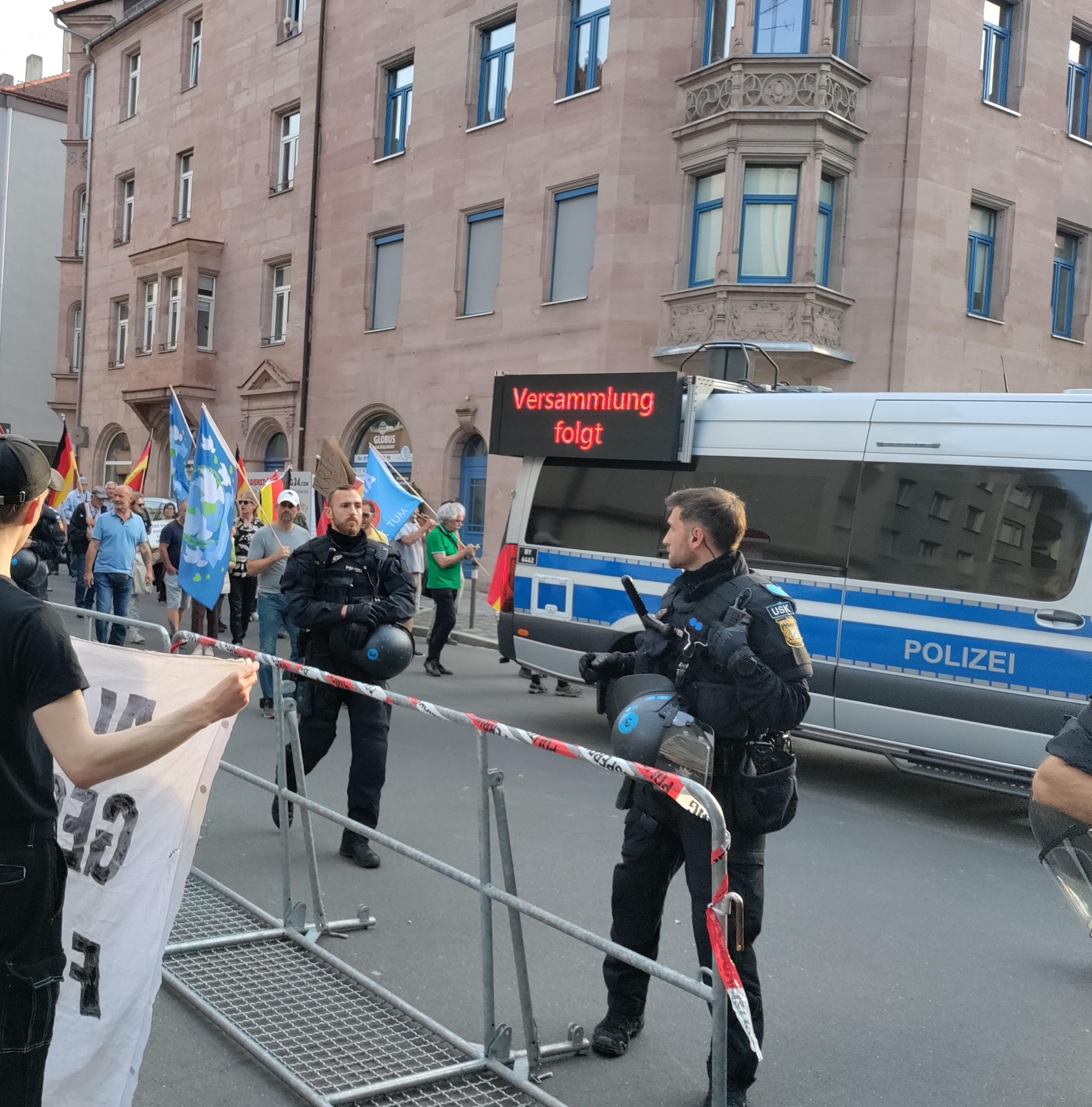 Versammlungsfahrzeug der cops, dahinter Nazis mit AfD, Deutschland und Friedensfahnen