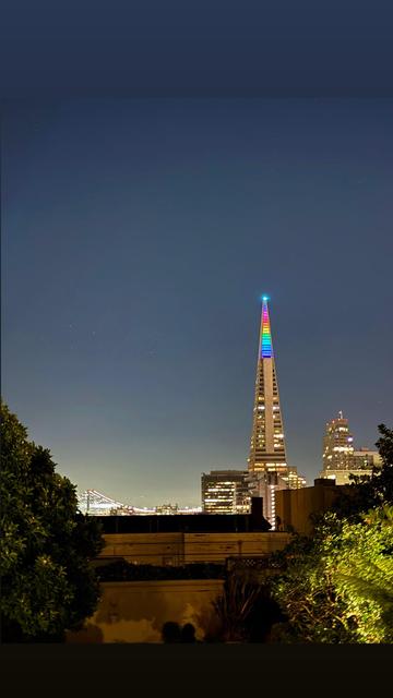 View of the Transamerica building in San Francisco the top of the pyramid is lit up in multiple colors for pride month.
