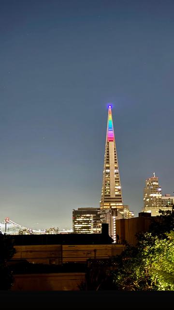 View of the Transamerica building in San Francisco the top of the pyramid is lit up in multiple colors for pride month.
