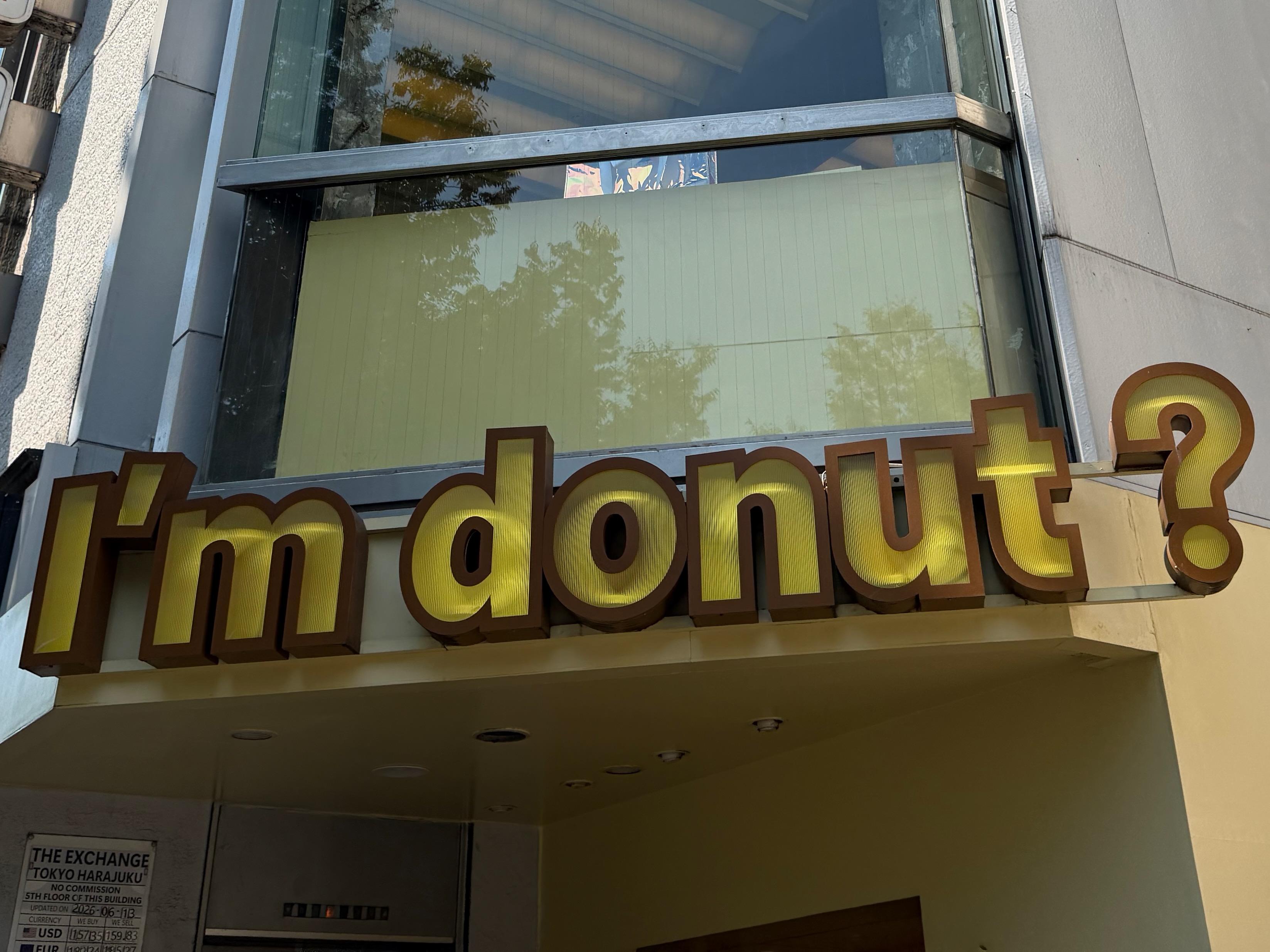 A large molded sign on the corner of a building below a window, reading "I'm donut?"