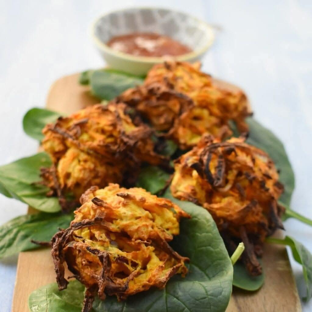 Crispy vegetable bhajis on a wooden board.