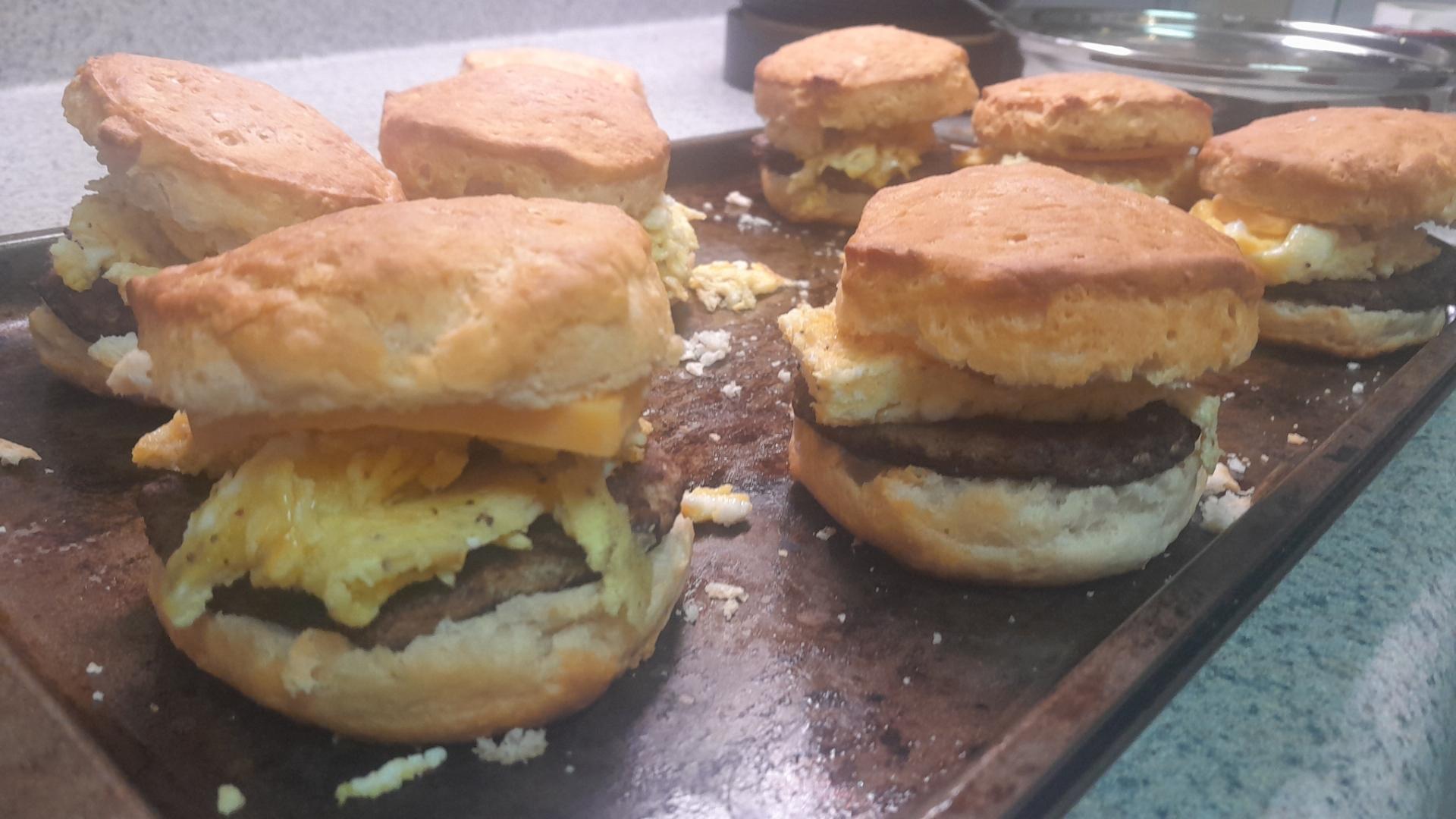 A baking pan with multiple home made sausage egg and cheese biscuits
