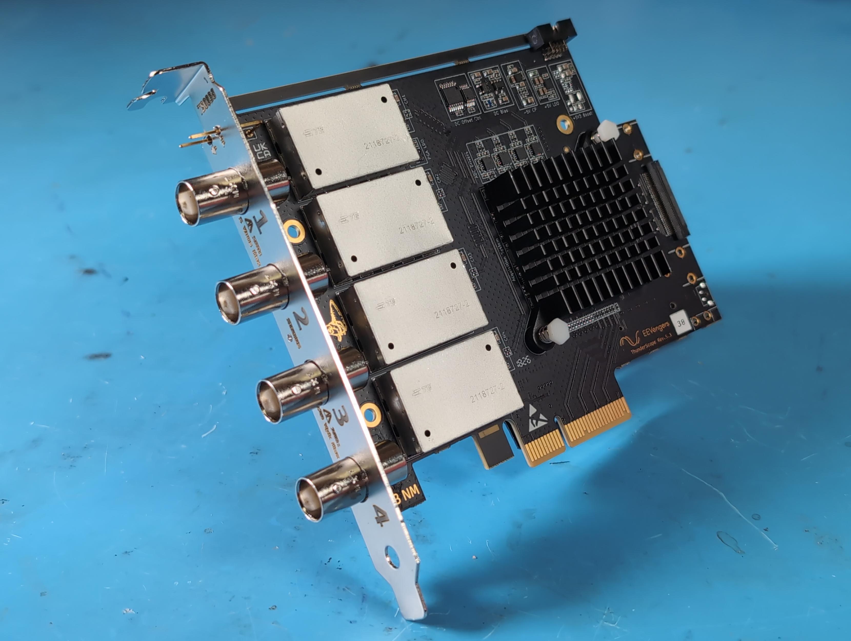 45 degree angle of a thunderscope pcie card, also propped up at about 45 degrees. you can see the pcie bracket engraved with channel numbers, the four front end shield cans, matte black pcb and heatsink