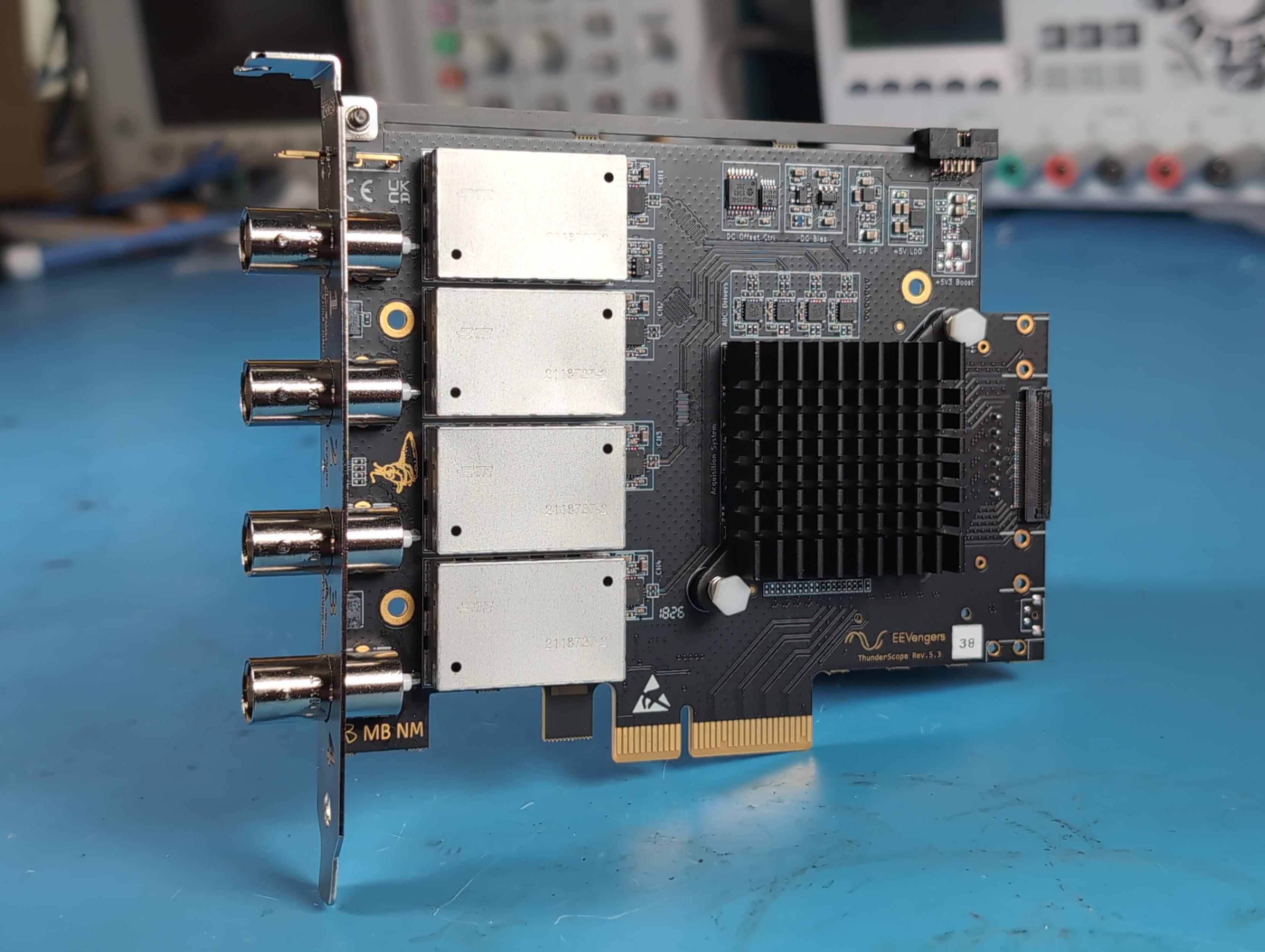 more direct angle of a thunderscope pcie card, propped up at about 90 degrees. you can see the pcie bracket engraved with channel numbers, the four front end shield cans, matte black pcb and heatsink