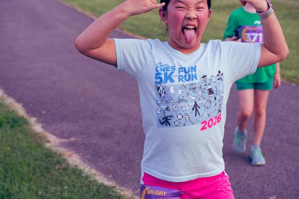 Young asian girl is sticking out her tounge and making a funny face with her hands up and the top of her head cut off by the top of the frame.