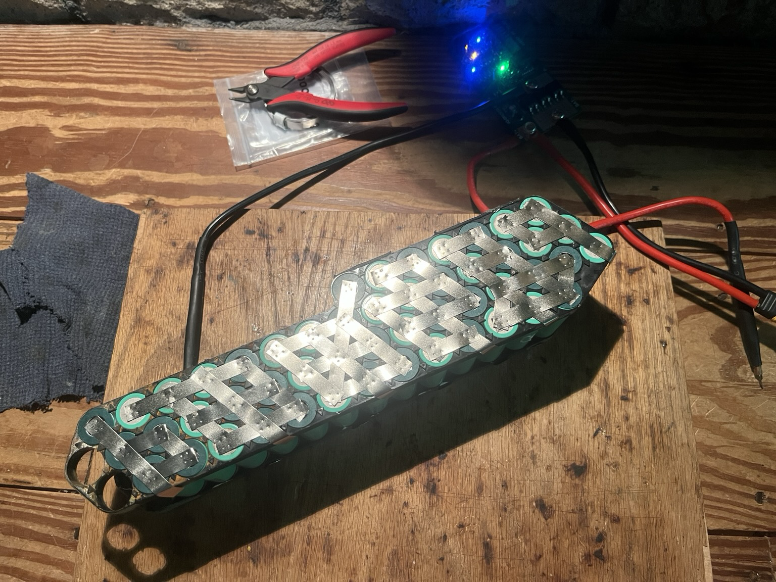 10S5P down tube battery pack with nickel strips welded to the 18650 cells. Powered on spot welder, flush cutters and a roll of nickel strip set beside the pack.