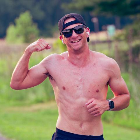 bare chested man wearing backwards billed cap and shades flexes muscle