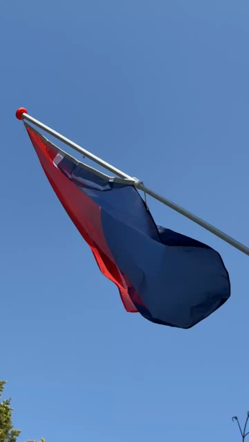 Wapperende Nederlandse vlag, waarbij het blauwe onderste deel als stijgend water inmiddels het wit en rood raakt