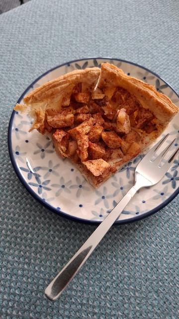 A piece of homemade apple pie on a small plate with a fork