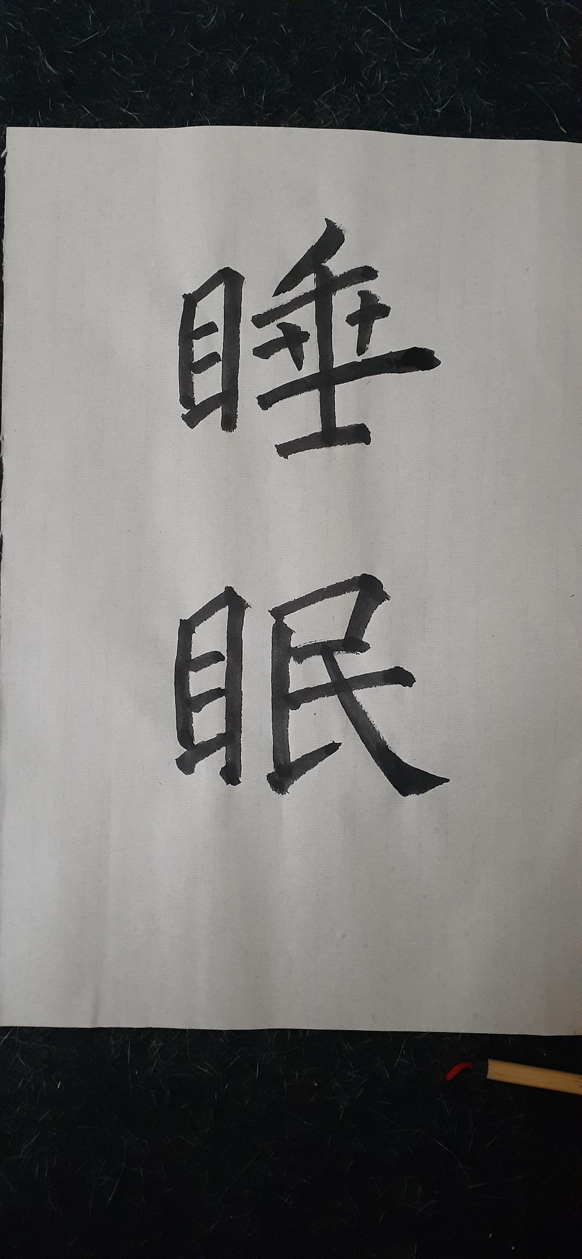 The Chinese characters for 'sleep' (shuìmiàn) written in regular script, black ink on brown bamboo paper.  The ink shows variation in colour and texture, from a thin dark green to a heavy black at the ends.