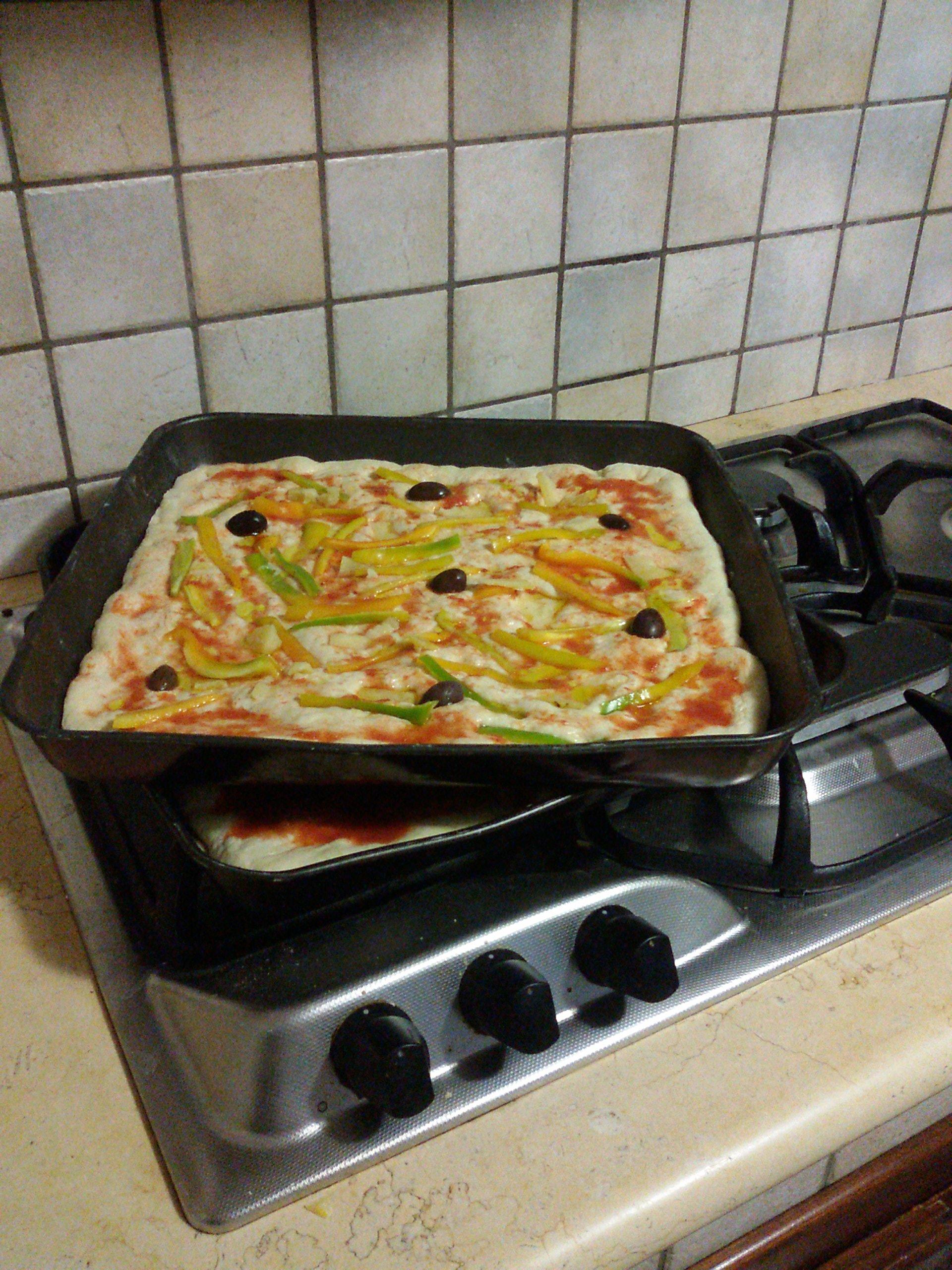 Photo of homemade pizzas featuring black olives, green and red bell peppers, and extra virgin olive oil.