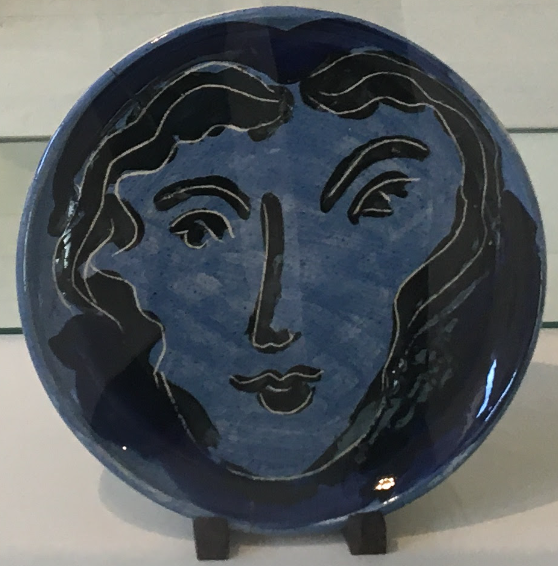 A dark blue plate with a face painted on it in black.