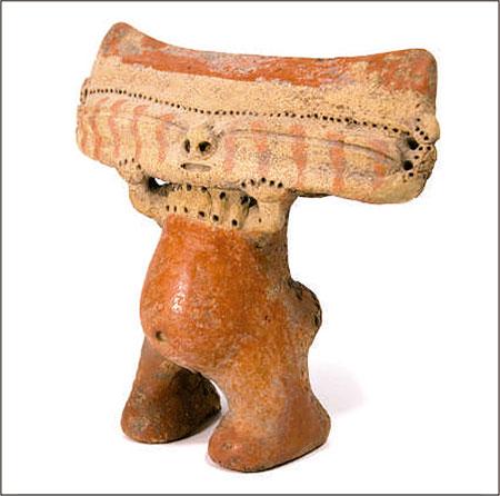 Figura de cuerpo pequeño, de apariencia infantil, con una cabeza rectangular con ojos cerrados que se extienden lateralmente.