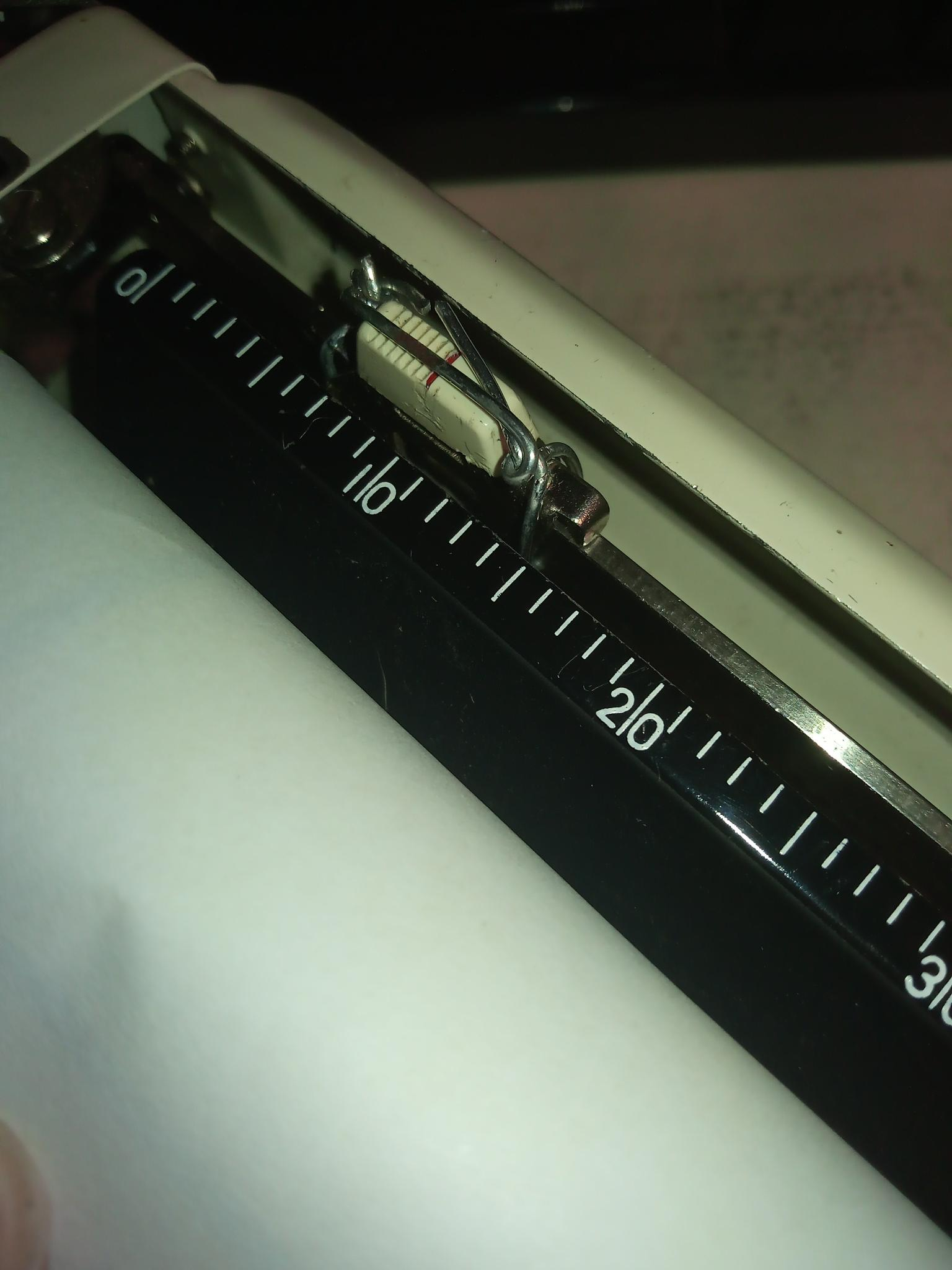 Close-up of a margin set control on a Brother Wizard Automatic typewriter. Someone smashed up the left margin. I unbent it, but it was distressed. The metal gave way despite attempts at being gentle. For a "fix that's good enough to use the typewriter most of the time," I have wired it into place at 1" with wire salvaged from a used-up spiral notebook.