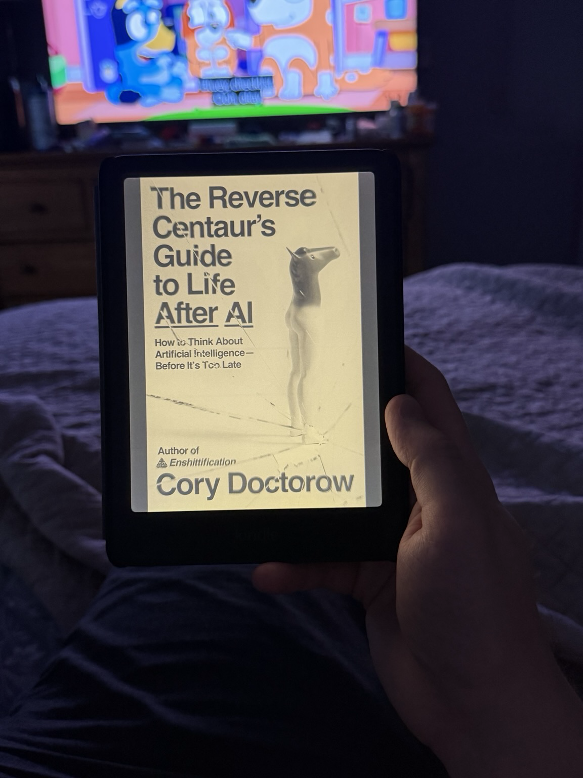 “The Reverse Centaur’s Guide to Life After AI” by Cory Doctorow on an e-reader with bluey playing in the background