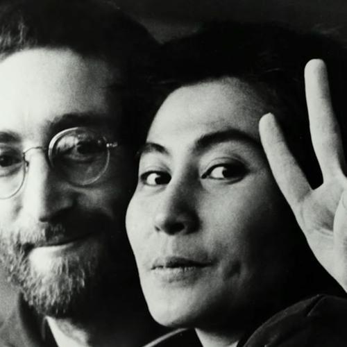 Black and white image of John Lennon and Yoko Ono. John is wearing his round wire rimmed glasses and smiling with a beard, while Yoko, in the foreground, is looking stoic, and holding up a vee, or peace sign with her fingers
