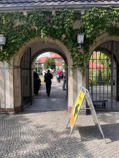 Eingangstor zum Gelände mit Menschen und Plakat Metropolcon