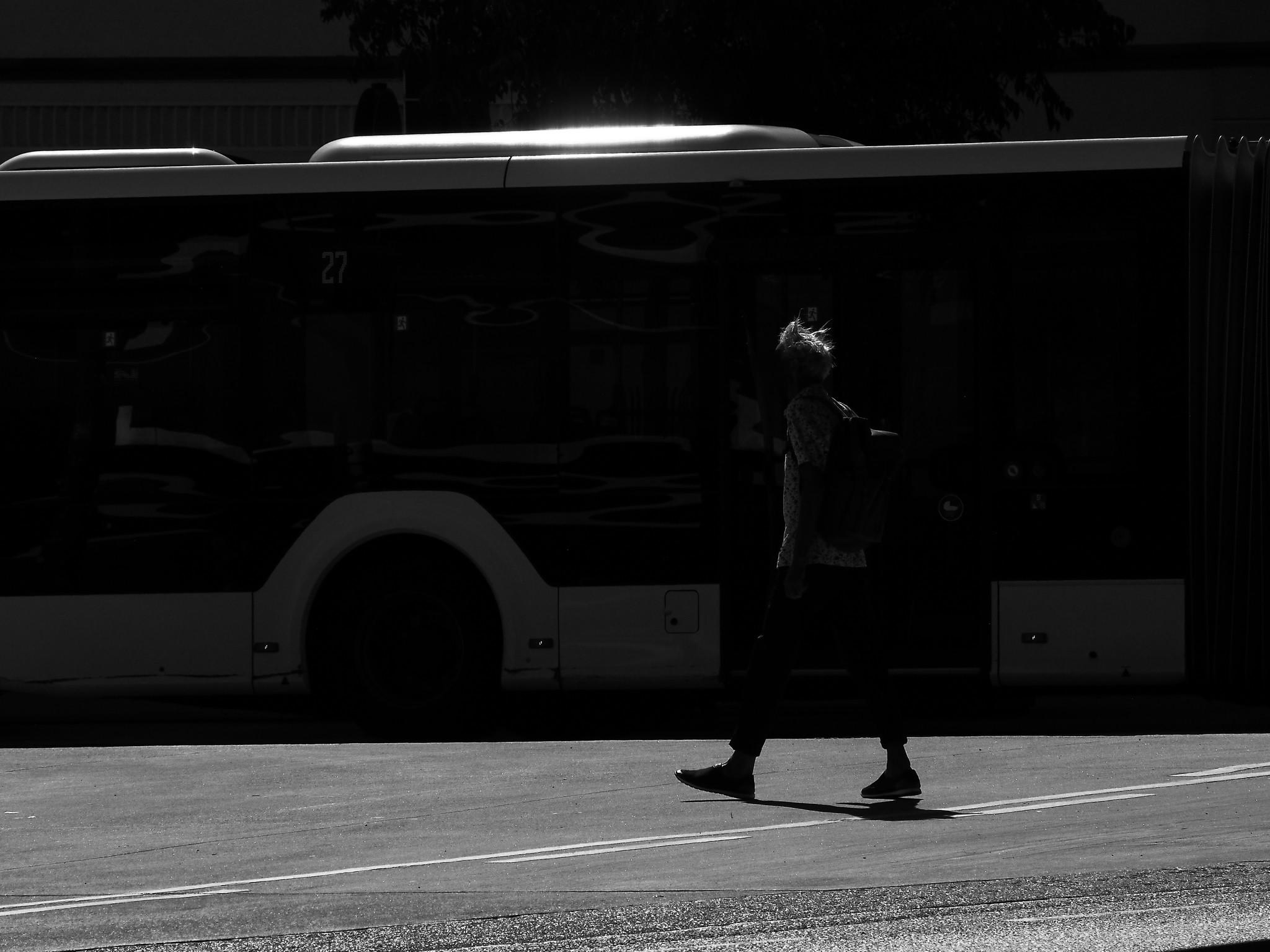 Dunkles Foto: Ein Mann mit verstrubbelten Haaren läuft im Sonnenschein über die Straße.