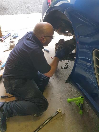 A mechanic putting a very light coating of copper-grease on the face of a Porsche Boxster wheel hub.
