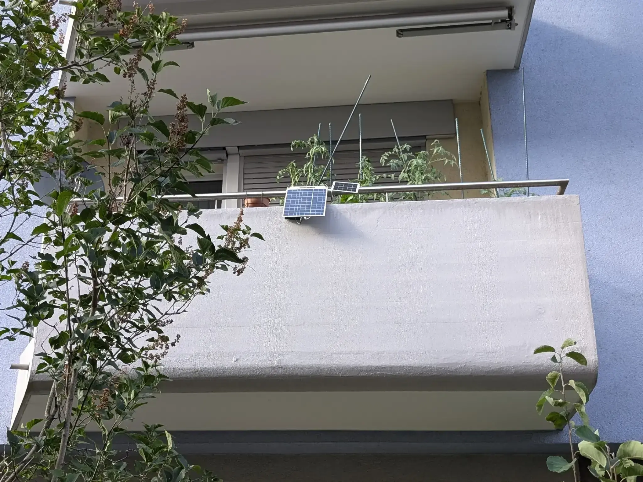Two incredibly tiny solar panels hanging off a balcony.