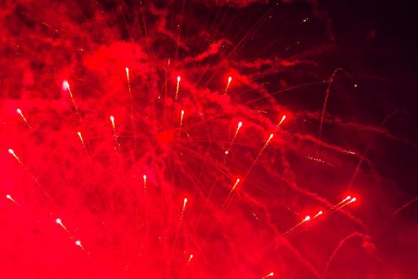 Short red streamers radiate out from a point off the bottom of the frame lighting up sqiuggly trails of smoke in the background,  i could swear I see a few stars in the dark part near the upper right