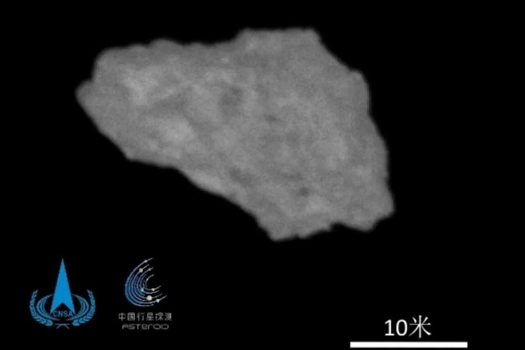 Picture of an unevenly shaped asteroid that is possibly a jagged fragment of Earth's moon. The logo for the China National Space Administration is in the lower left corner. Taken by Tianwen-2.