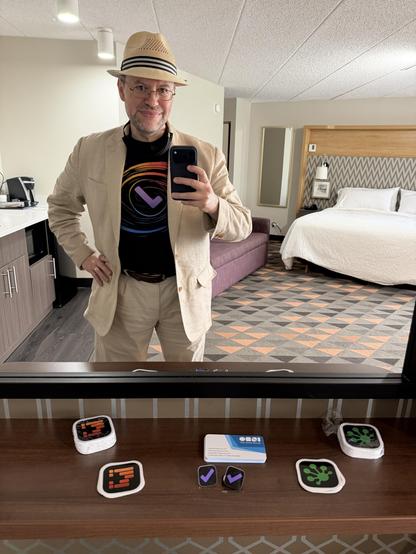 Me taking a picture of myself in the mirror, above a shelf holding an assortment of stickers and pins for OmniOutliner 6, OmniFocus 4, and OmniGraffle 8.