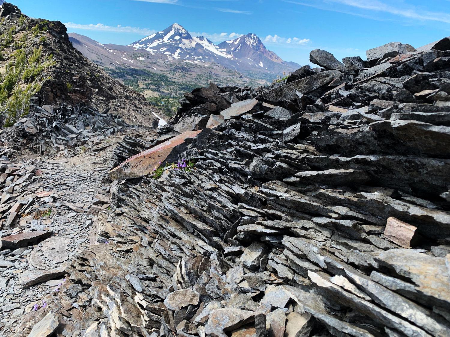 Pile of shale-like rock layers, with Middle and North Sister in the background.