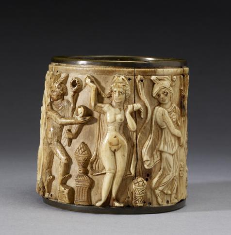 Byzantine Circular Pyxis depicting the Judgement of Paris. We see Hermes, Aphrodite, Athene. Hermes holds his kerykeion staff and the golden apple "for the fairest". He turns away from a nude Aphrodite who is crafted with labia. Beside her, Athene, fully clothed, throws her a disapproving look.