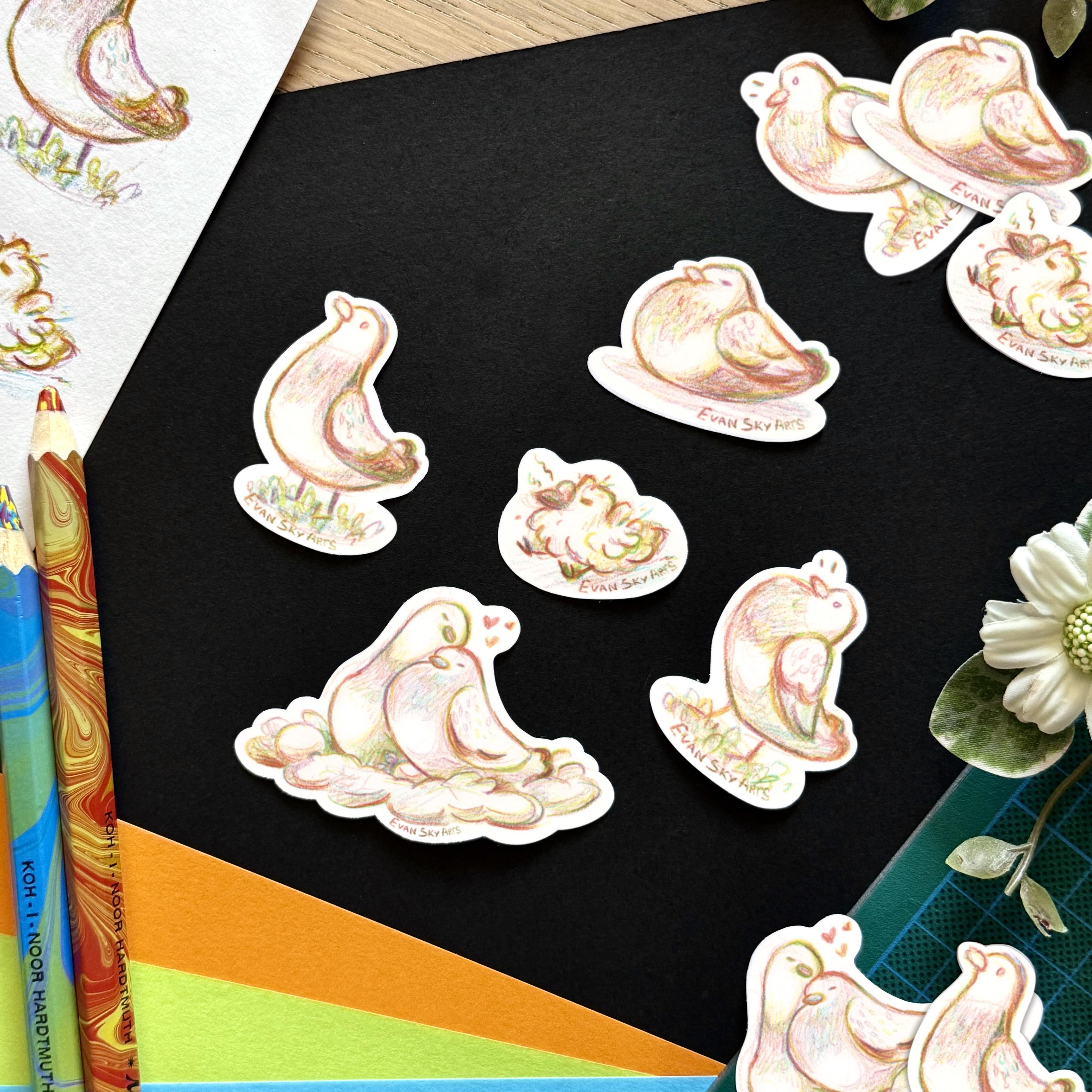 Picture of 5 stickers set on a black background framed with colourful papers, more stickers, two different tricolour pencils as well as decorative plants. Each sticker is of a different pigeon sketched with the tricolour pencils. One is a pigeon couple snuggling in a nest, another is a flirty pigeon with a puffed chest, there’s also a pigeon happily resting on the floor, a standing pigeon, and in the middle is a baby pigeon.