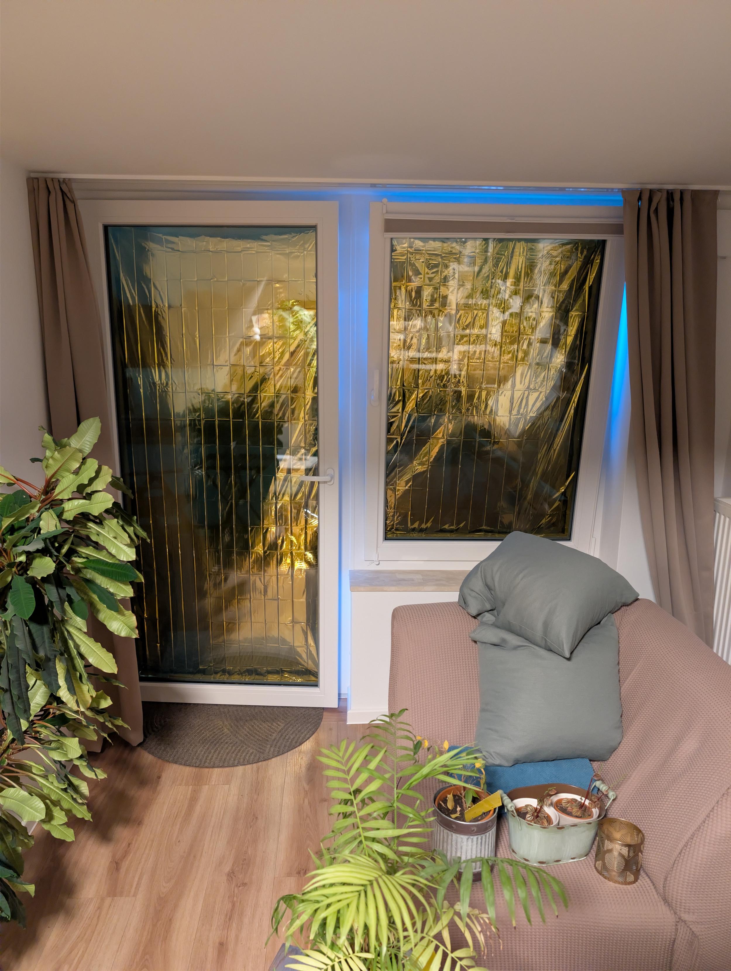 Zu sehen sind 1 Balkontür daneben ein Fenster, die jeweils mit einer Rettungsdecke abgeklebt sind. Das Foto wurde von innen gemacht.